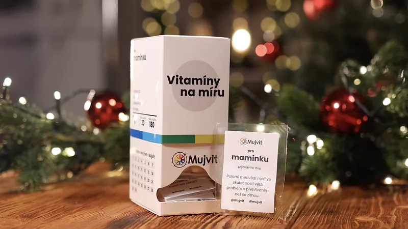 Krabička Vitamíny na míru Mujvit a denní sáček s oslovením pro maminku na dřevěném stole před vánočním stromkem